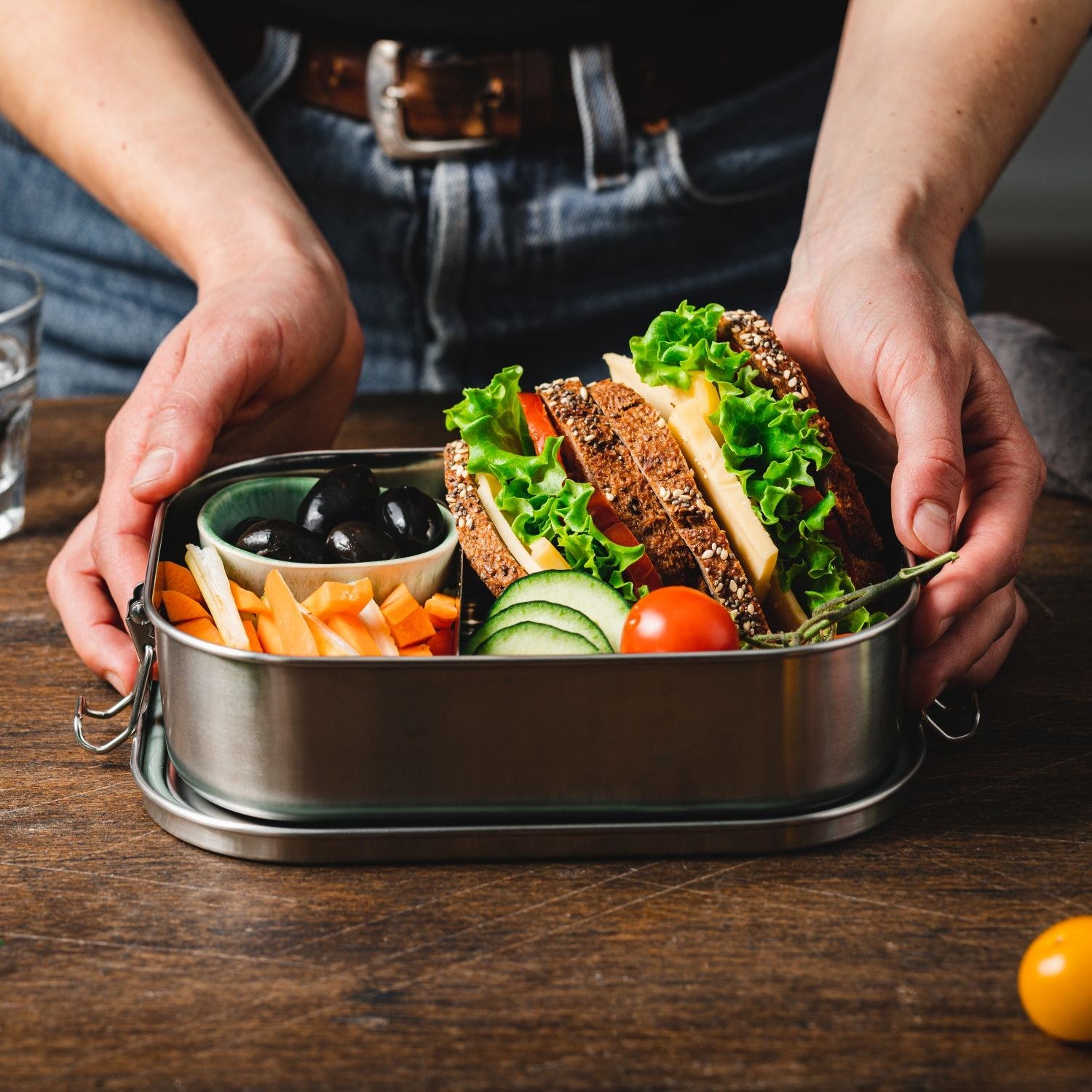 Brotzeitdose mit einem belegten Brot und Gemüsesticks