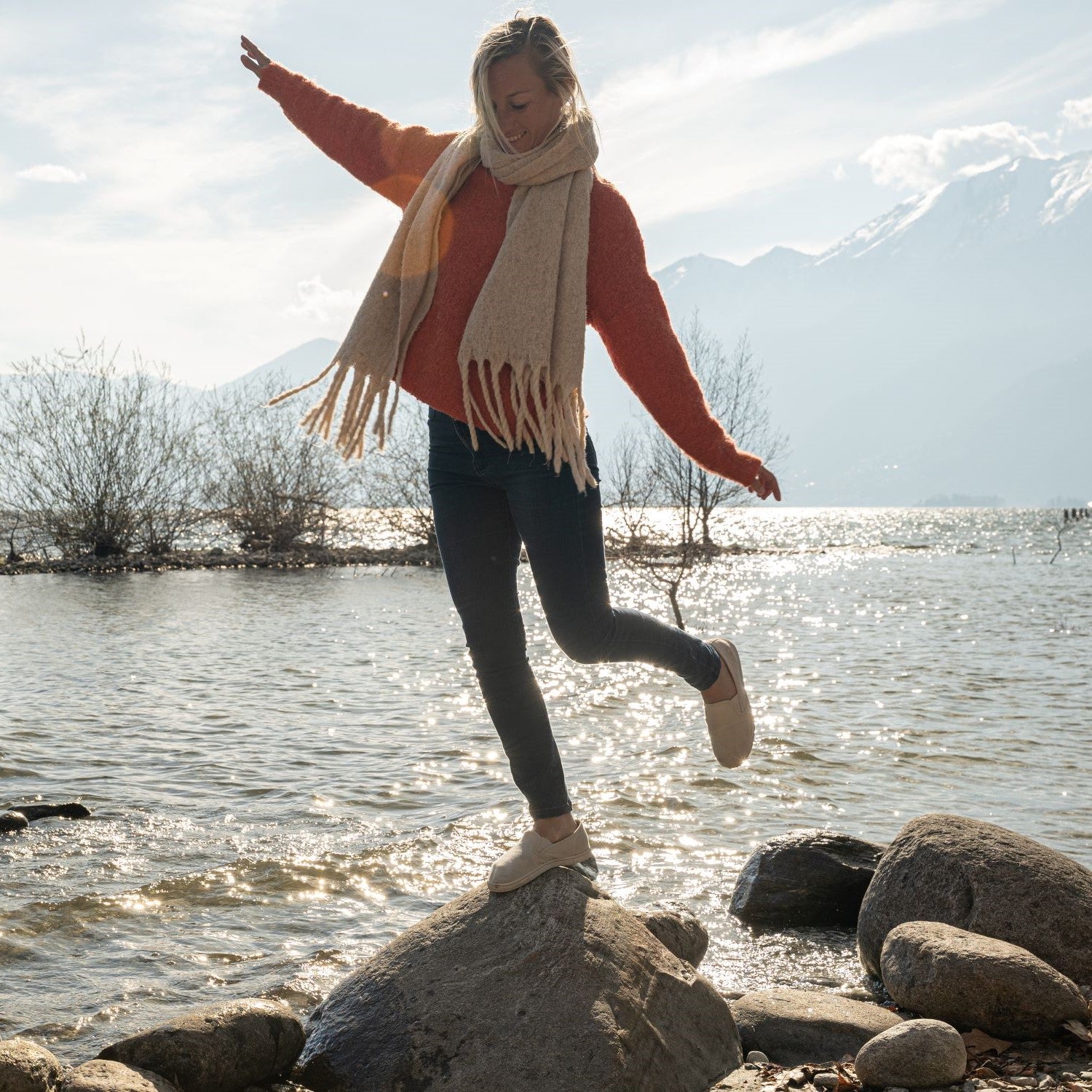 Frau balanciert an einem See auf einem großen Stein