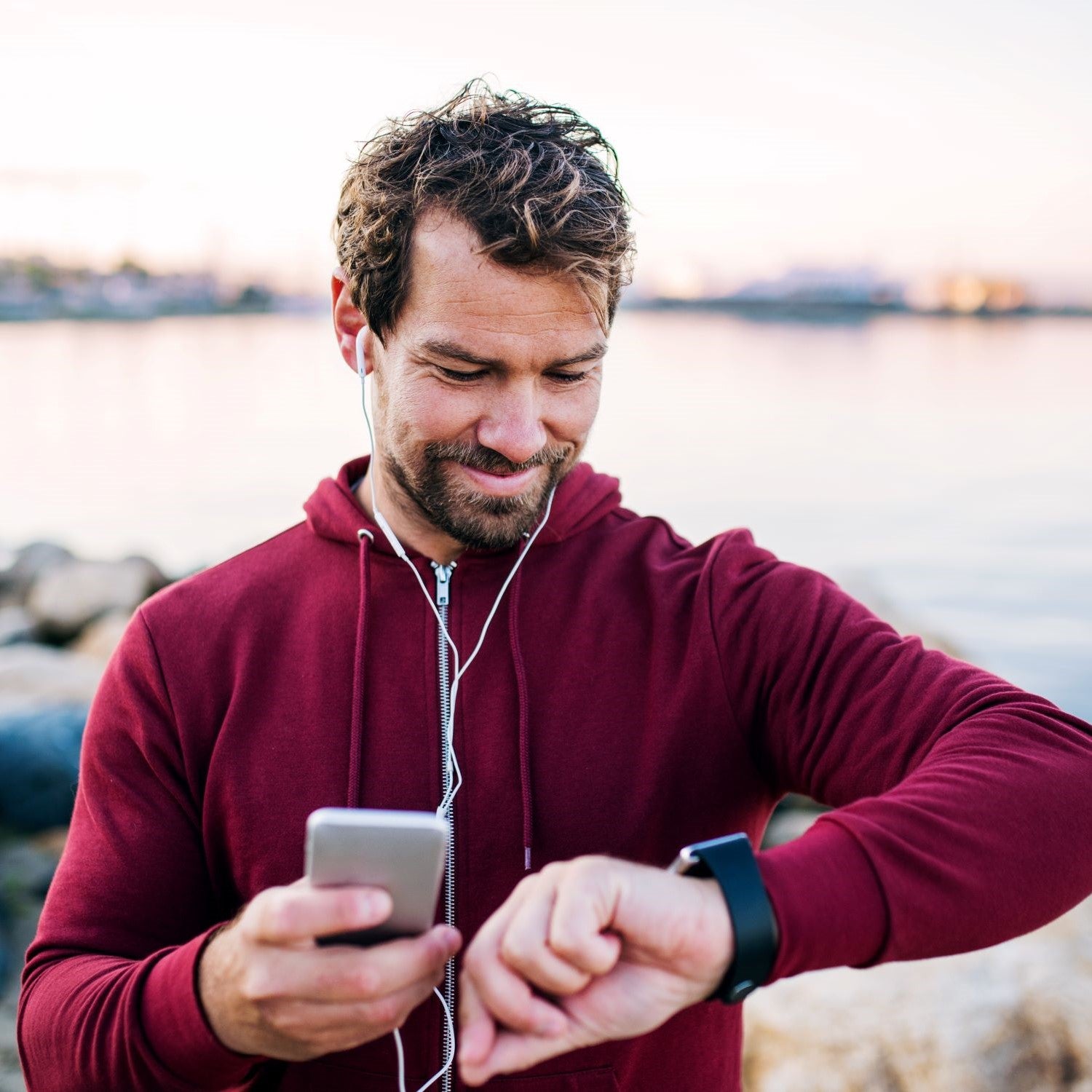 Mann joggt um einen See und misst seine Leistung mit einer Trackinguhr