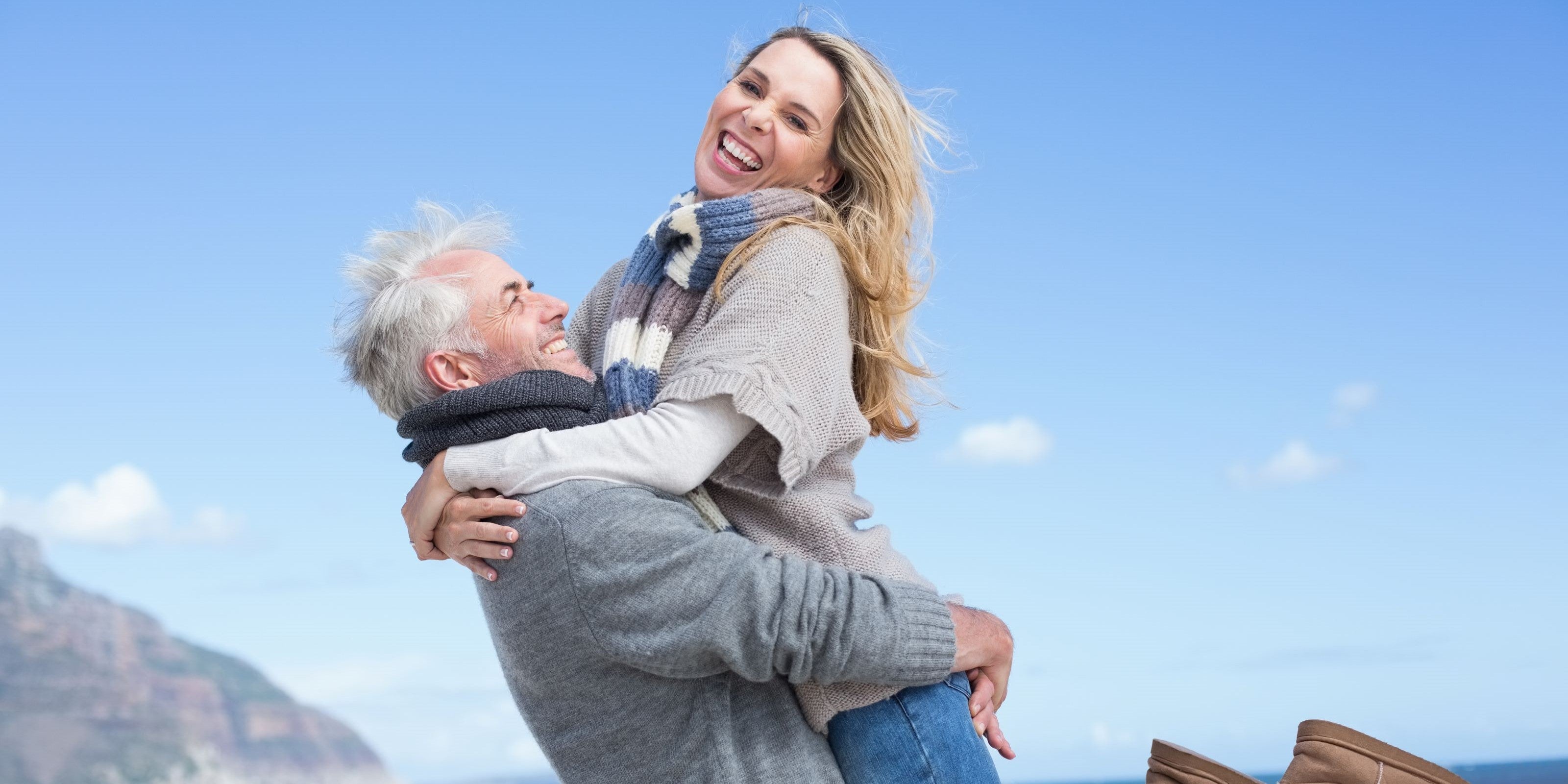 Mann hebt seine Frau am Strand hoch