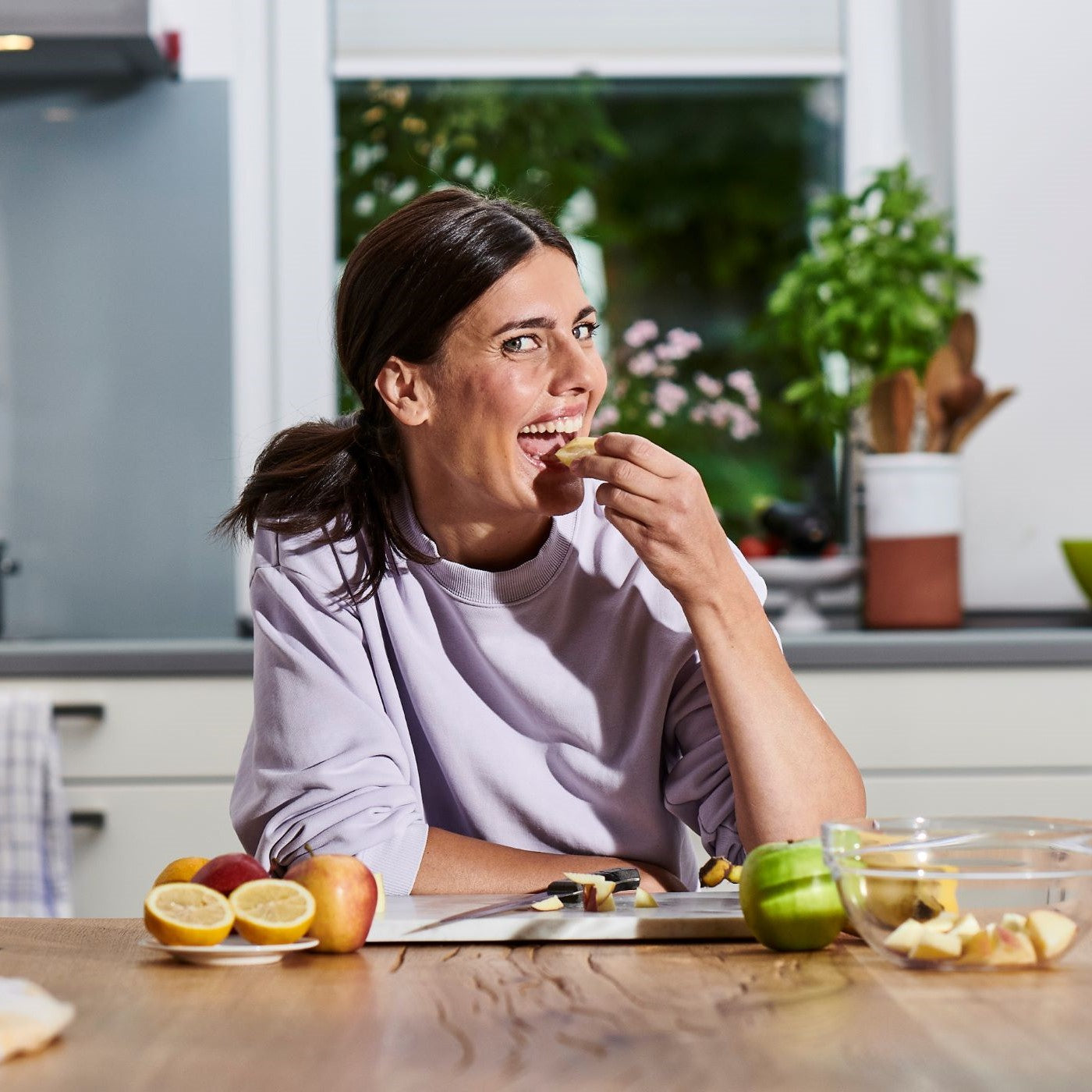 Frau isst Obst in der Küche