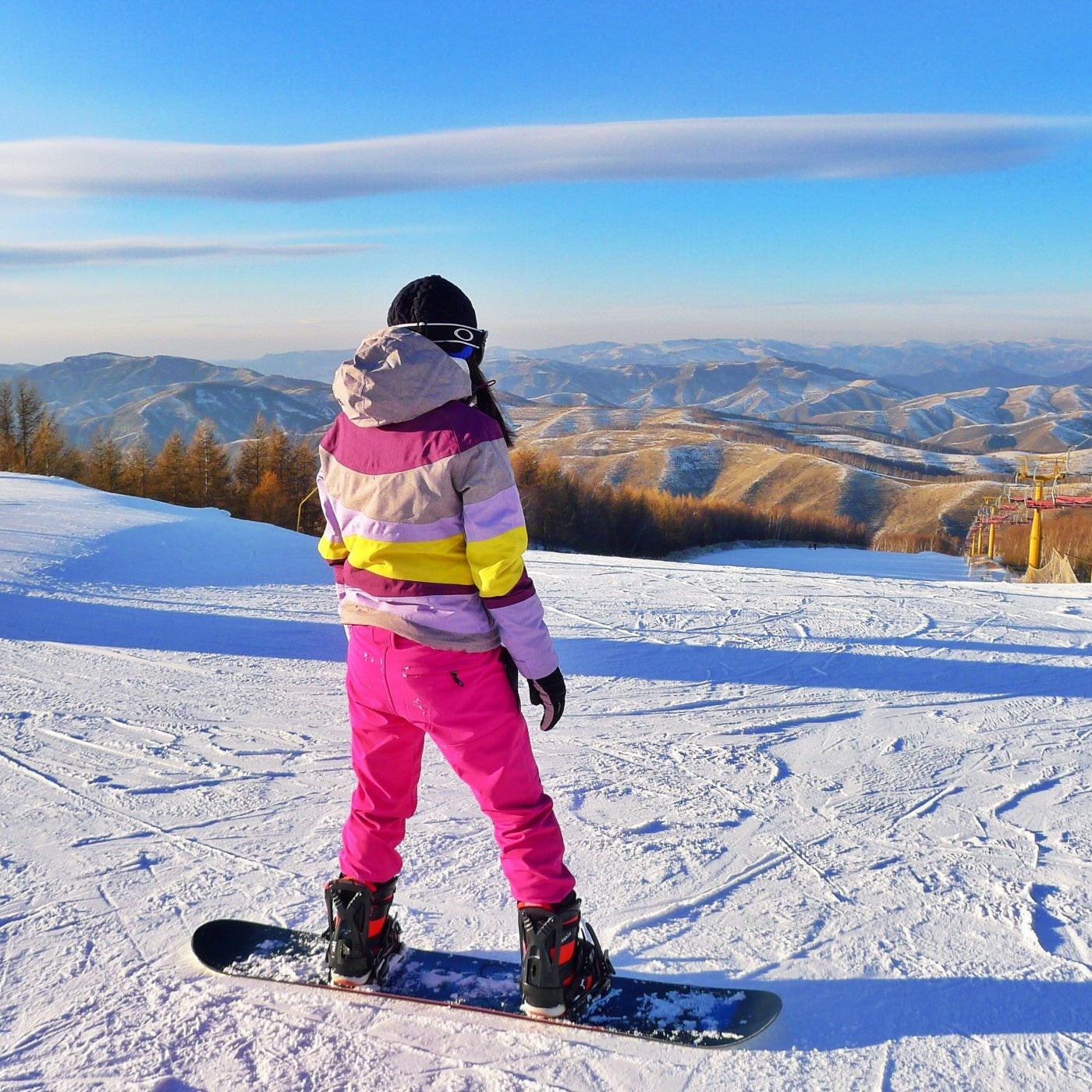 Frau steht auf einem Snowboard auf der Piste