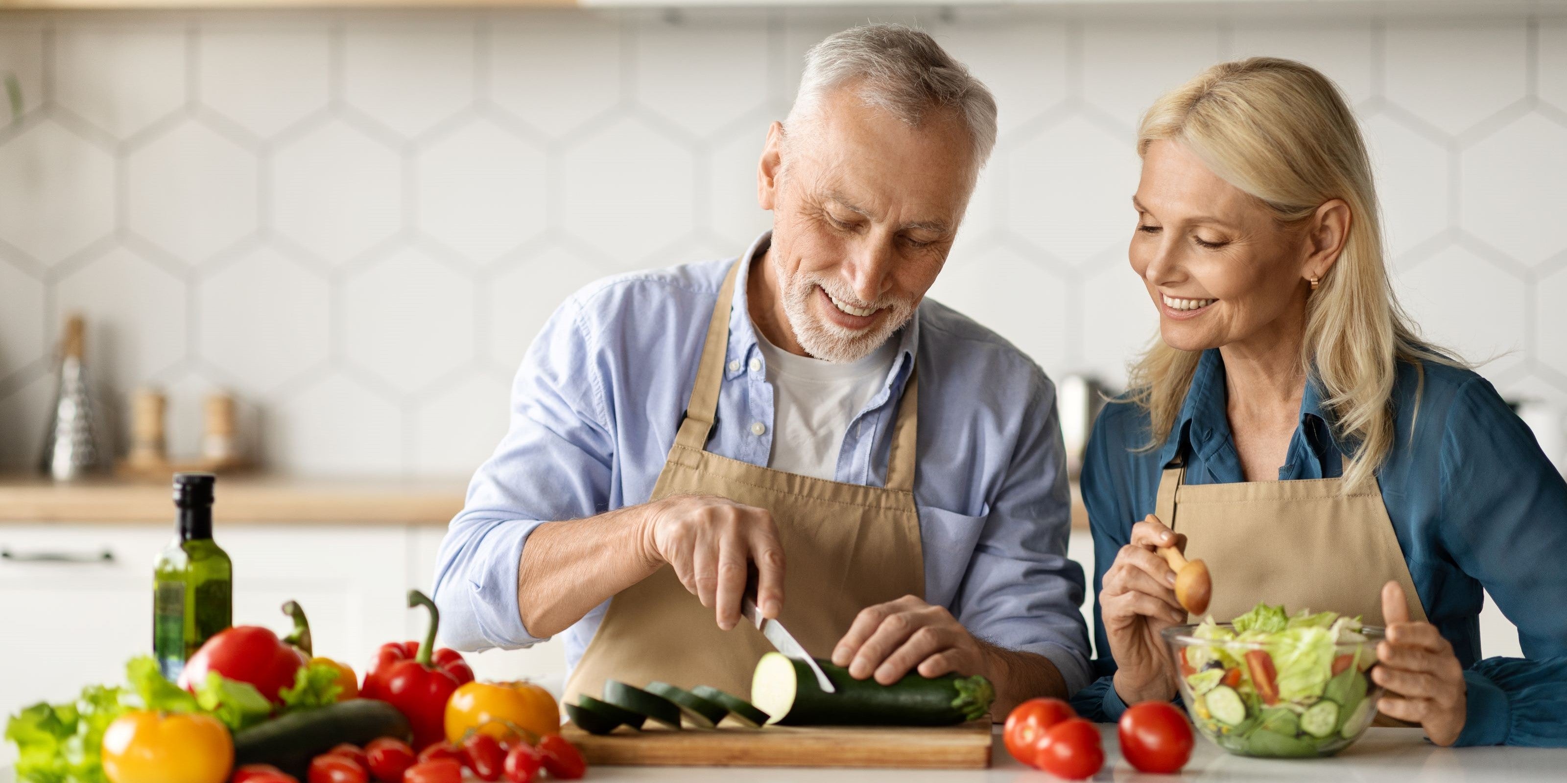 Älteres Paar schneidet Gemüse in der Küche
