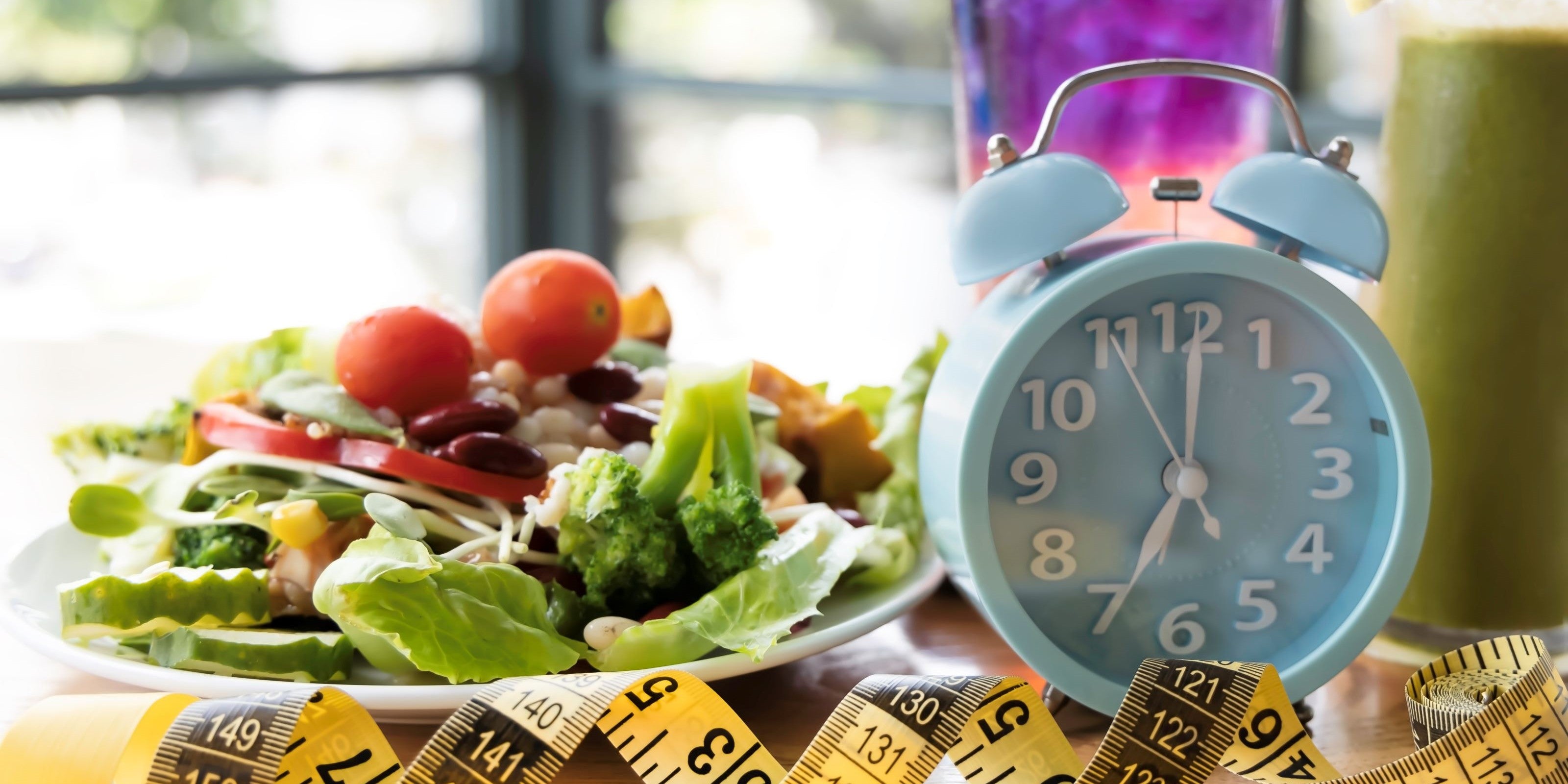 Symbolbild fürs Intervallfasten mit Wecker, Maßband und Salat