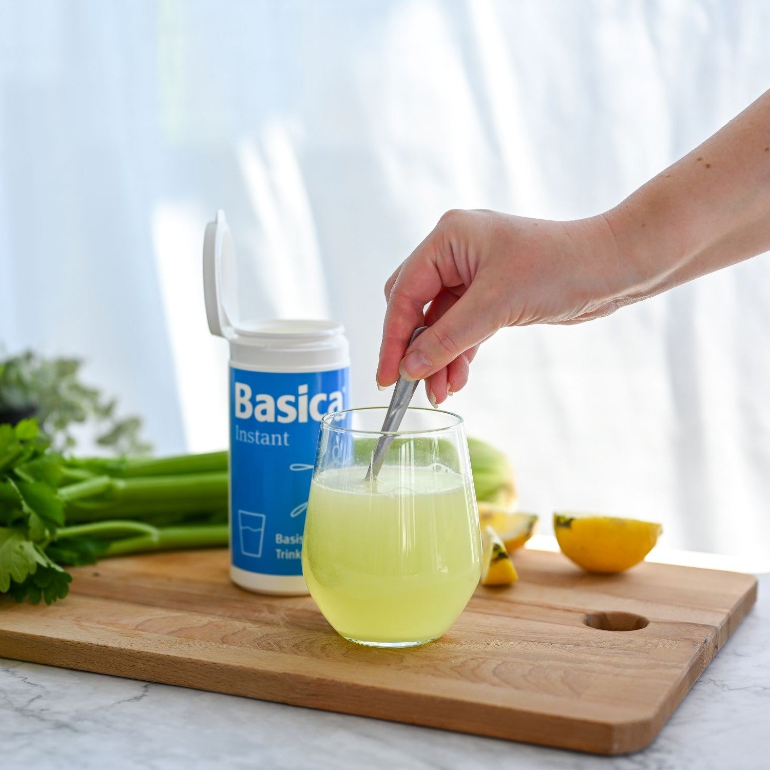 Frau rührt Basica Instant in ein Glas mit Wasser