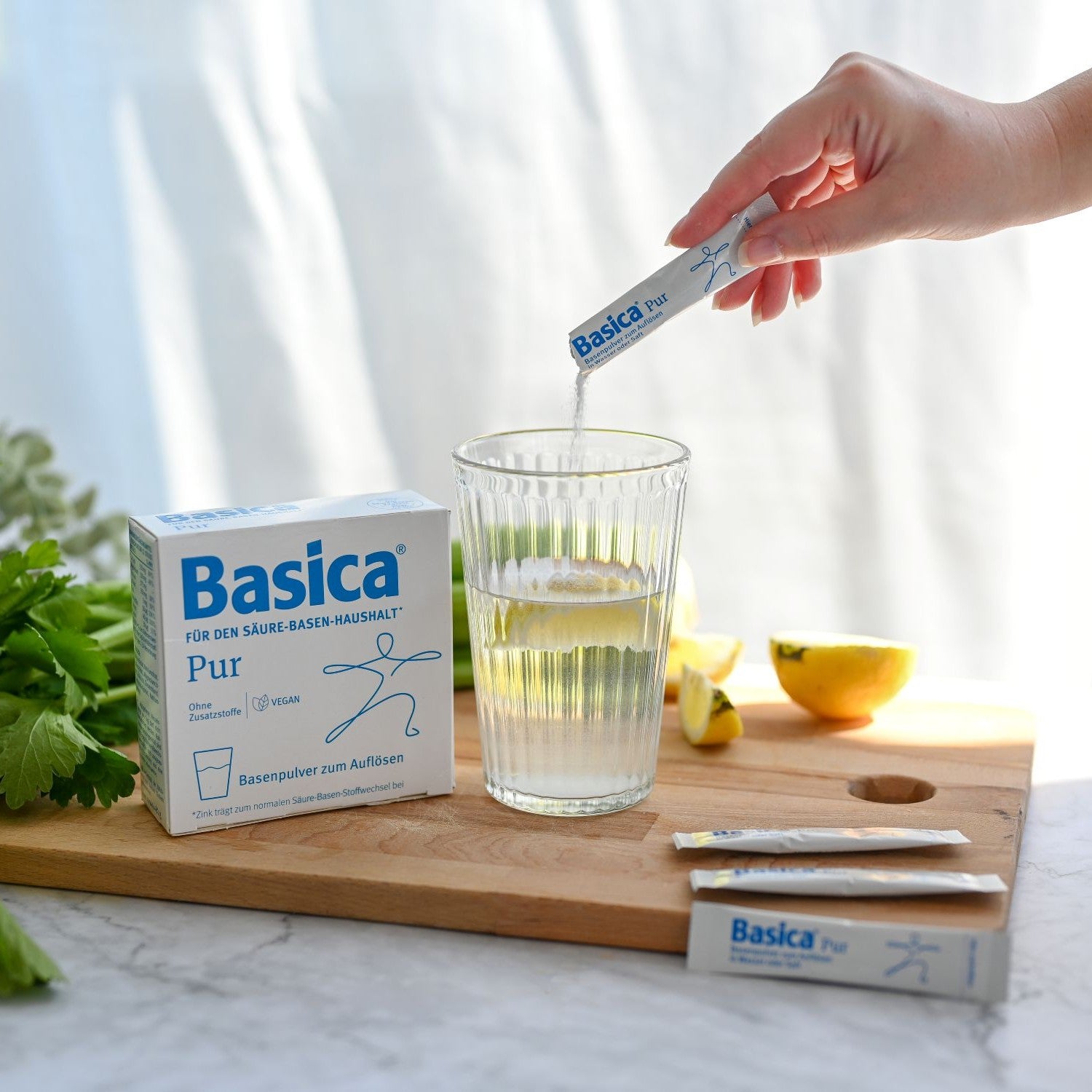 Frau schüttet einen Basica Pur Stick in ein Wasserglas