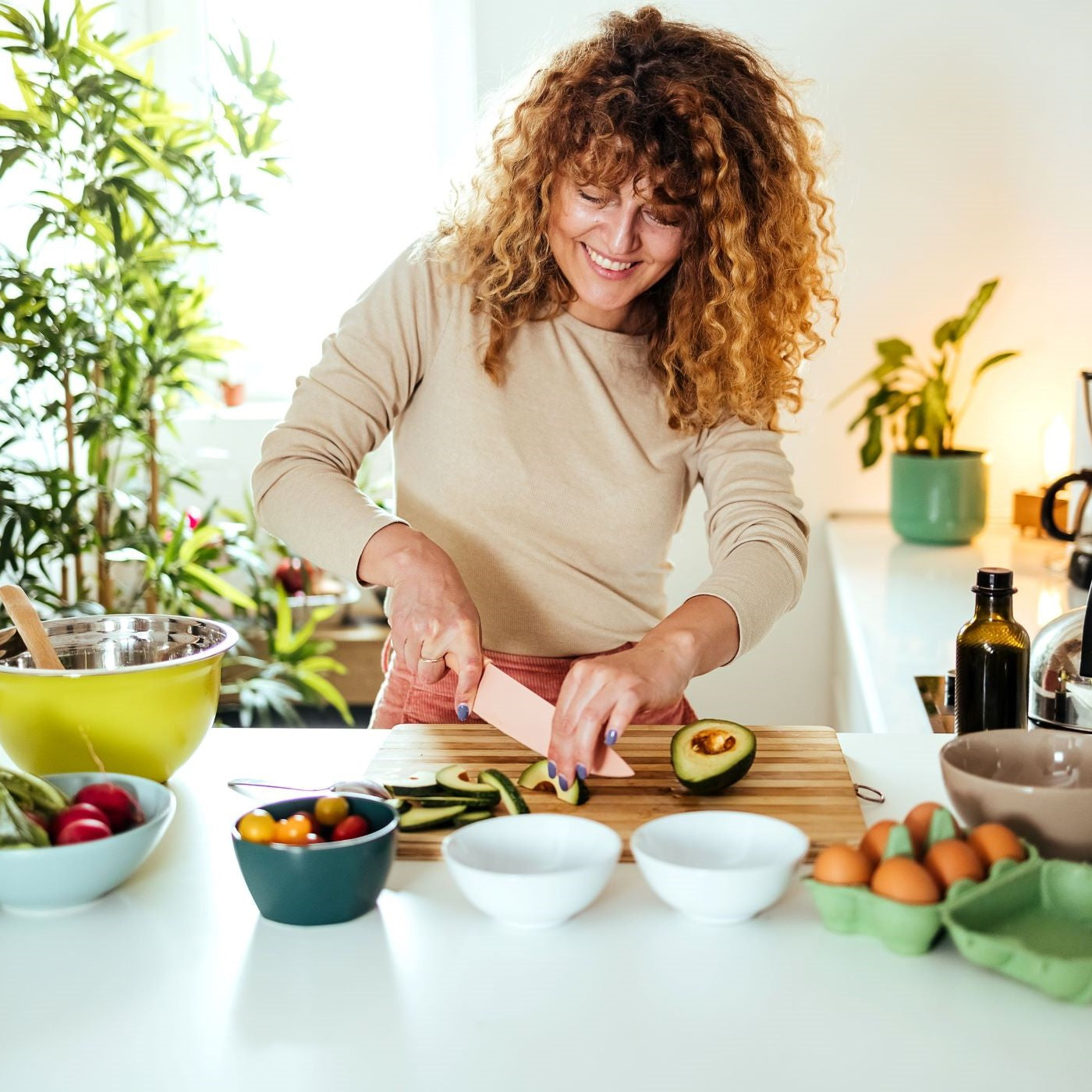 Frau schneidet Avocados in der Küche