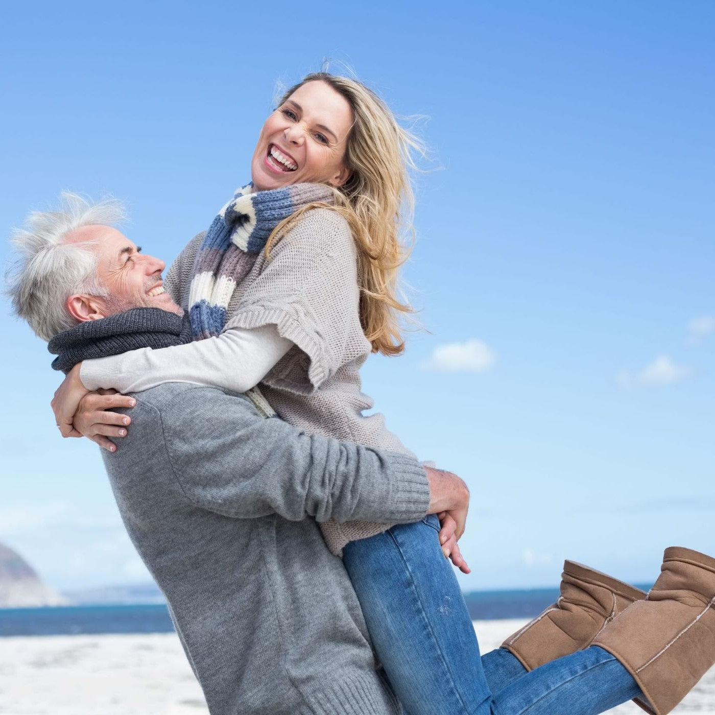 Mann hebt seine Frau am Strand hoch