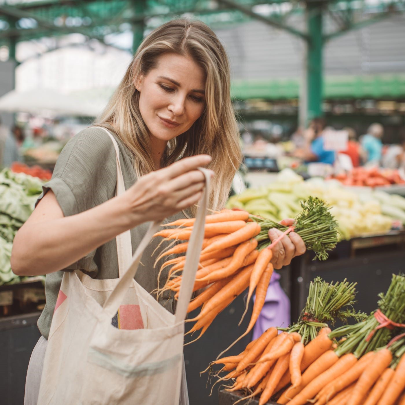Frau kauft Karotten auf dem Wochenmarkt