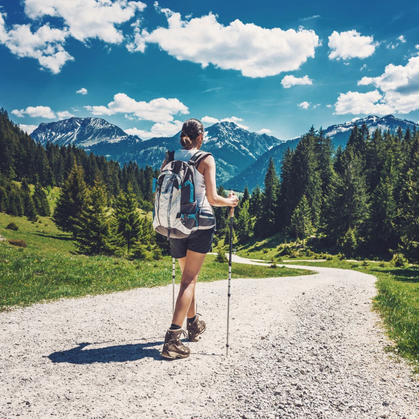 Frau wandert mit Wanderstöcken mit Bergkulisse