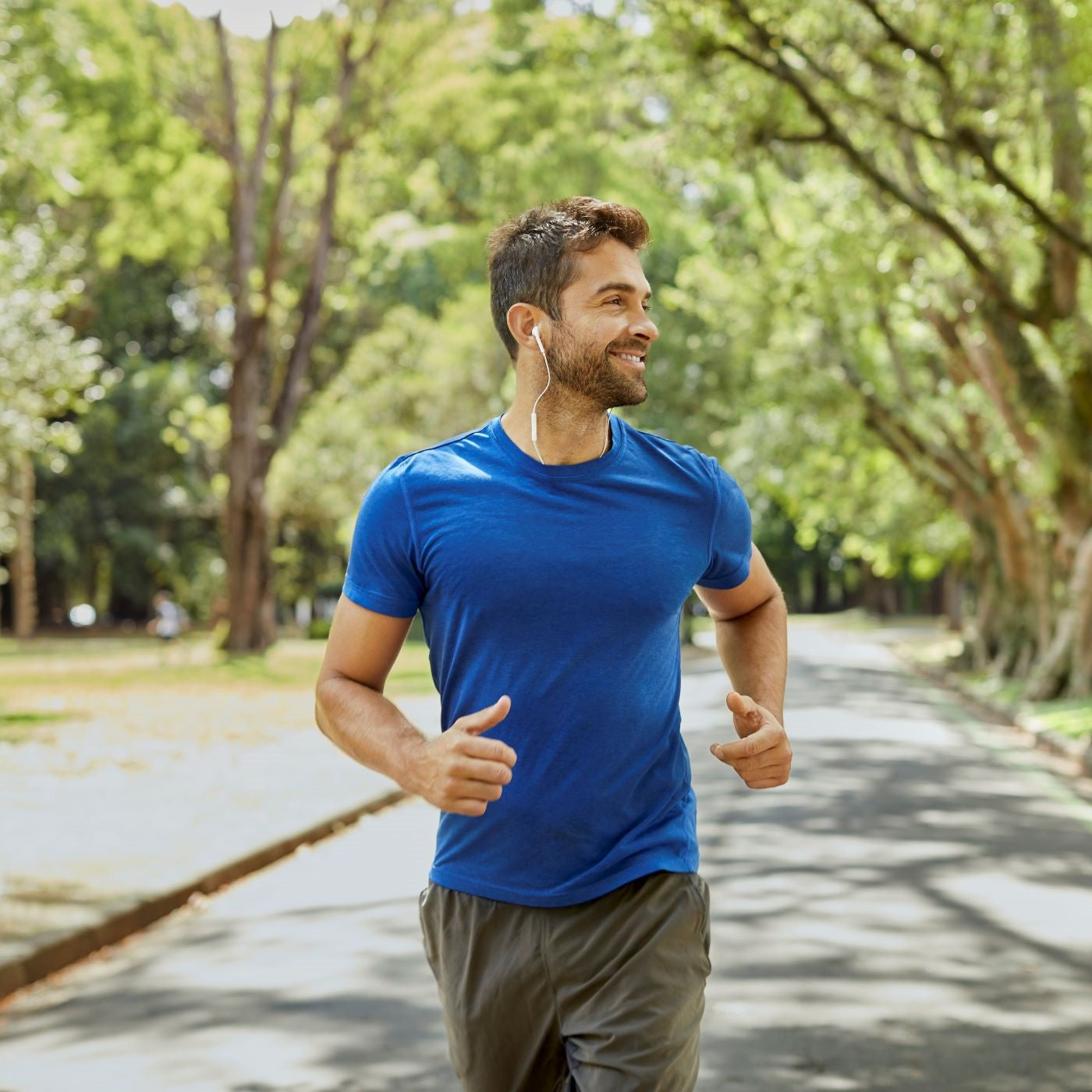 Mann joggt mit Kopfhörern durch den Park
